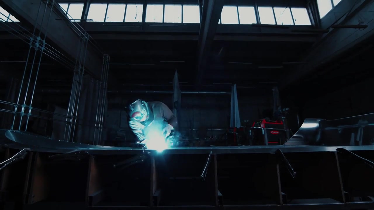 Een vakman last een aluminium AQUASPIRIT-romp in de fabriek